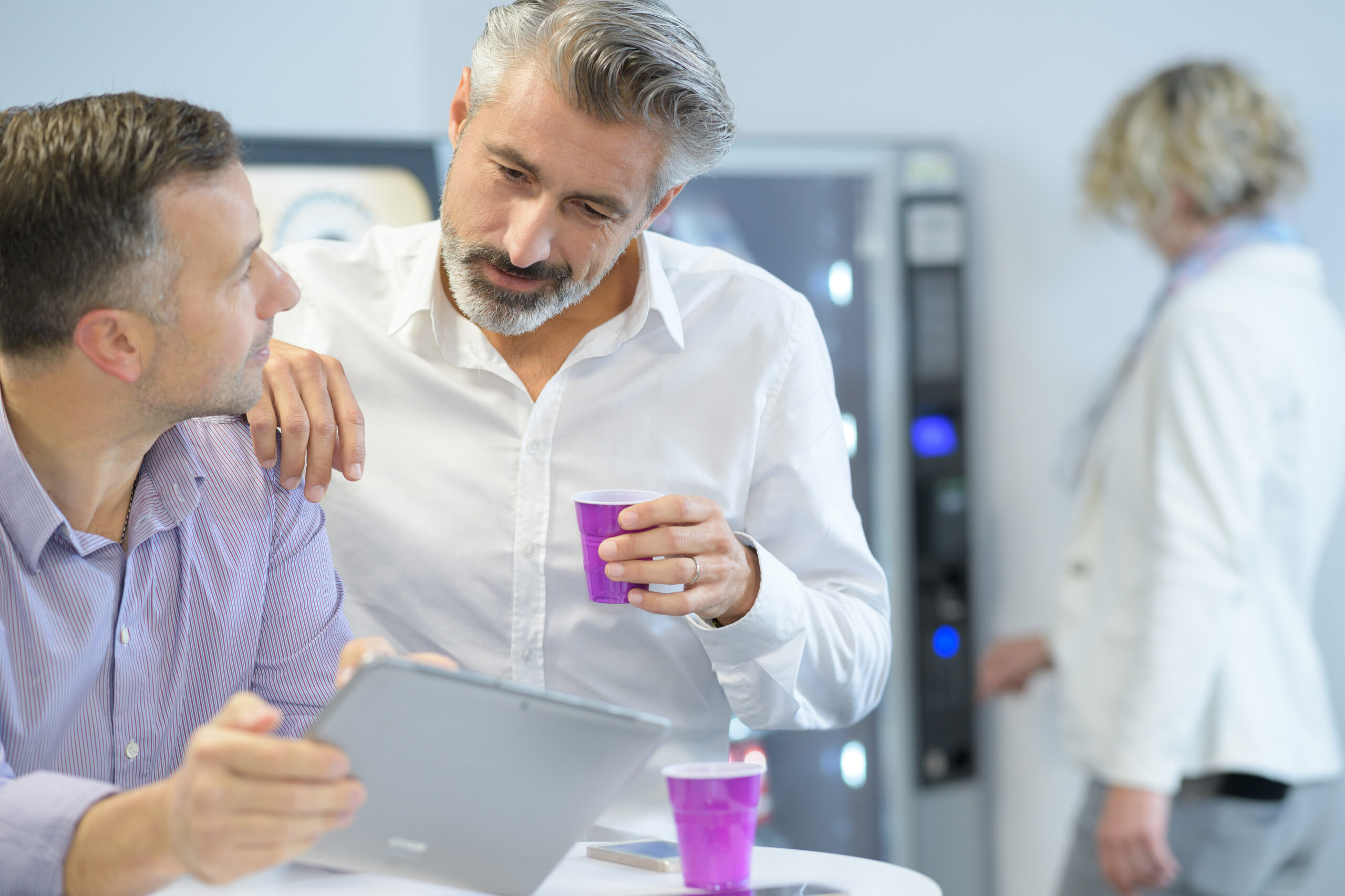 Colleghi durante una pausa caffè in azienda, con distributori automatici sullo sfondo