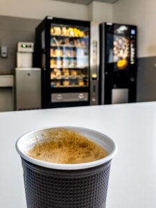 Bicchiere di caffè su un tavolo con distributori automatici sullo sfondo